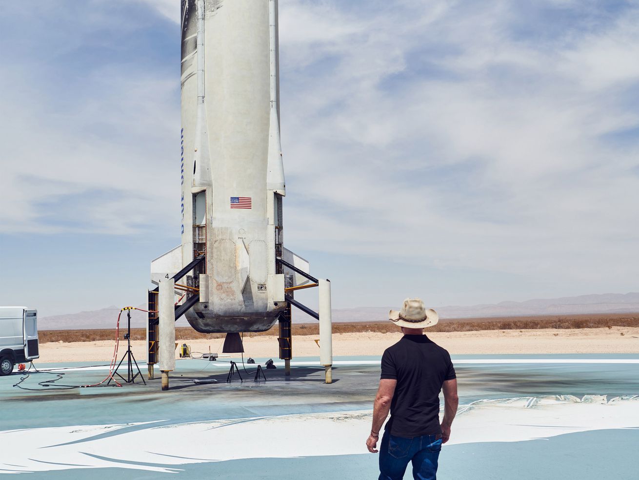 Jeff Bezos stands looking at the Blue Origin rocket on its launchpad.