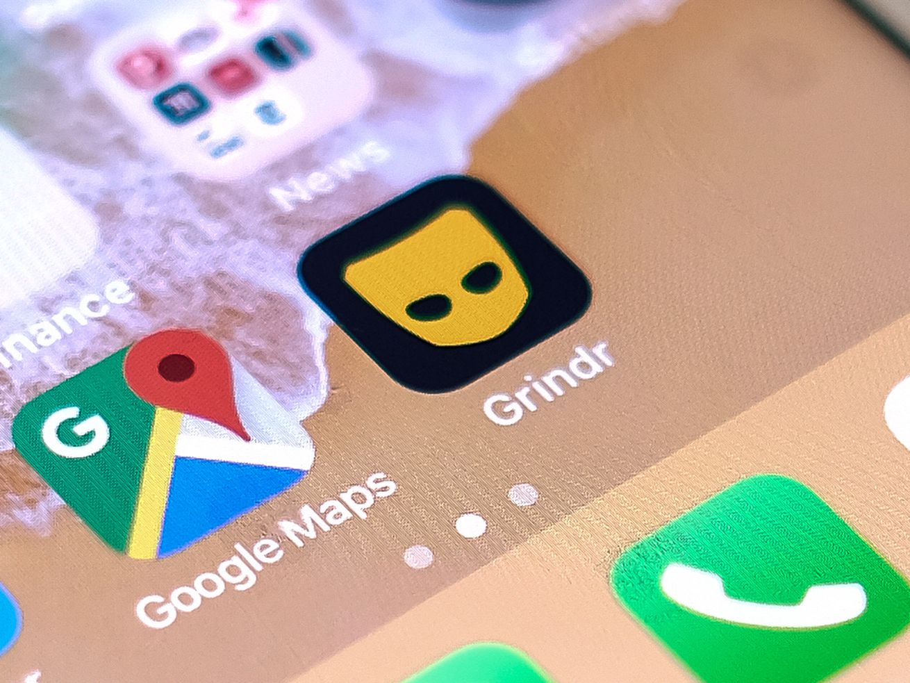 Dating app Grindr next to the Google Maps app on an iPhone screen.
